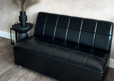 Modern black sofa in Mirahbell Hair Studio, Bristol, England, GB. Elegant salon seating area.