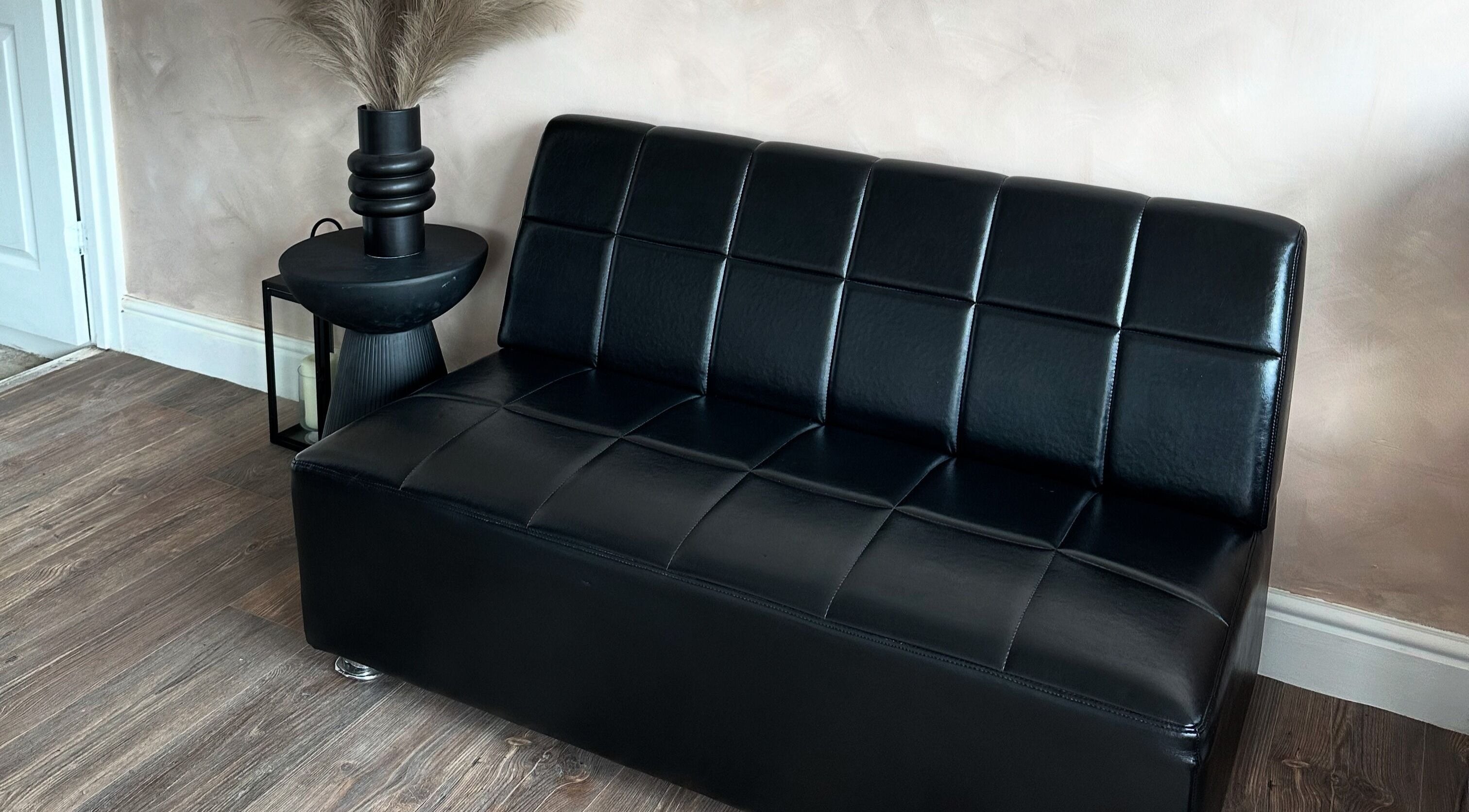 Modern black sofa in Mirahbell Hair Studio, Bristol, England, GB. Elegant salon seating area.