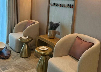 زاوية استرخاء في Therapeutic Touch، الخبر، المنطقة الشرقية، السعودية، تضم كراسي مريحة وطاولة أنيقة.
