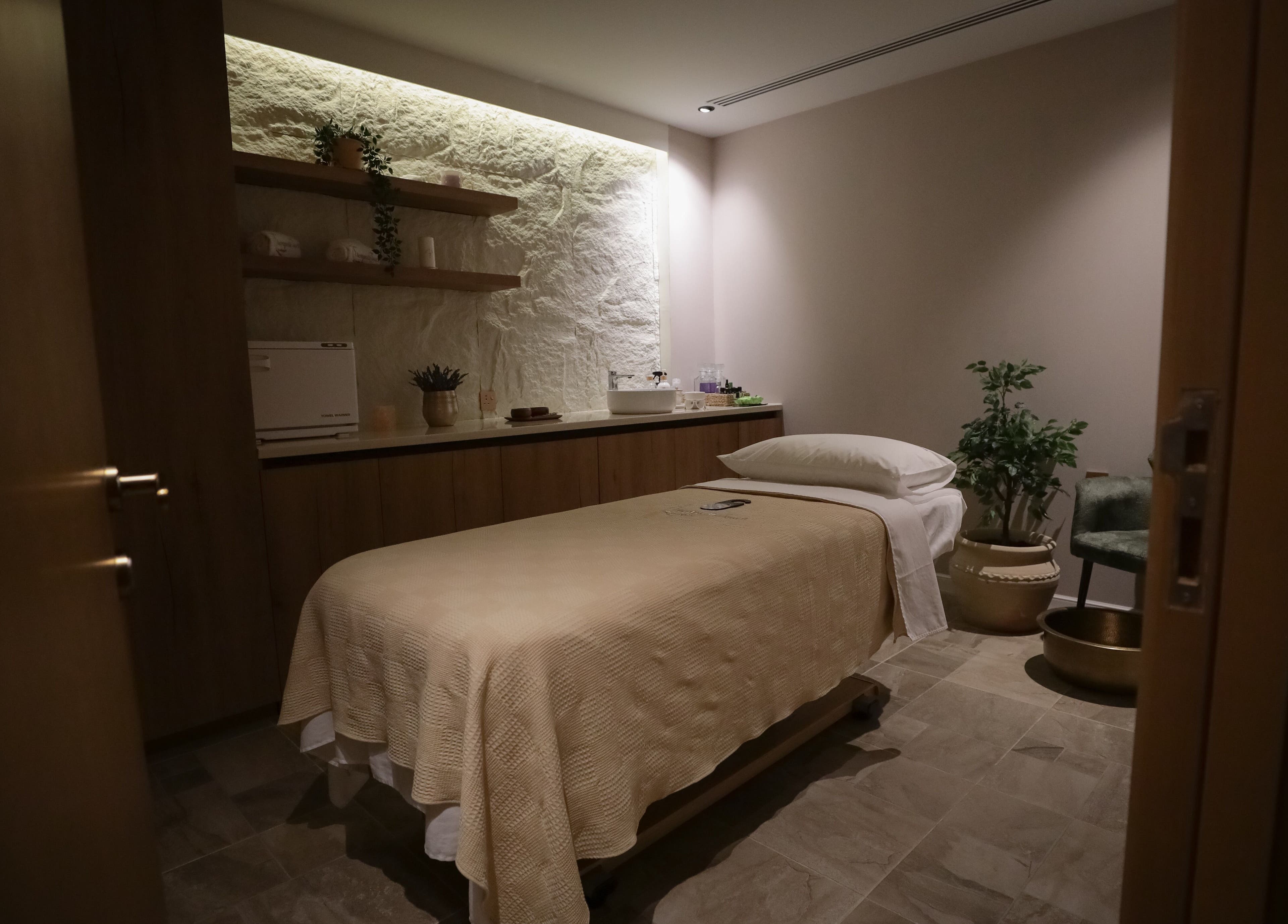 غرفة سبا مريحة في Therapeutic Touch، الخبر، المنطقة الشرقية، السعودية، مع سرير تدليك ونباتات هادئة.