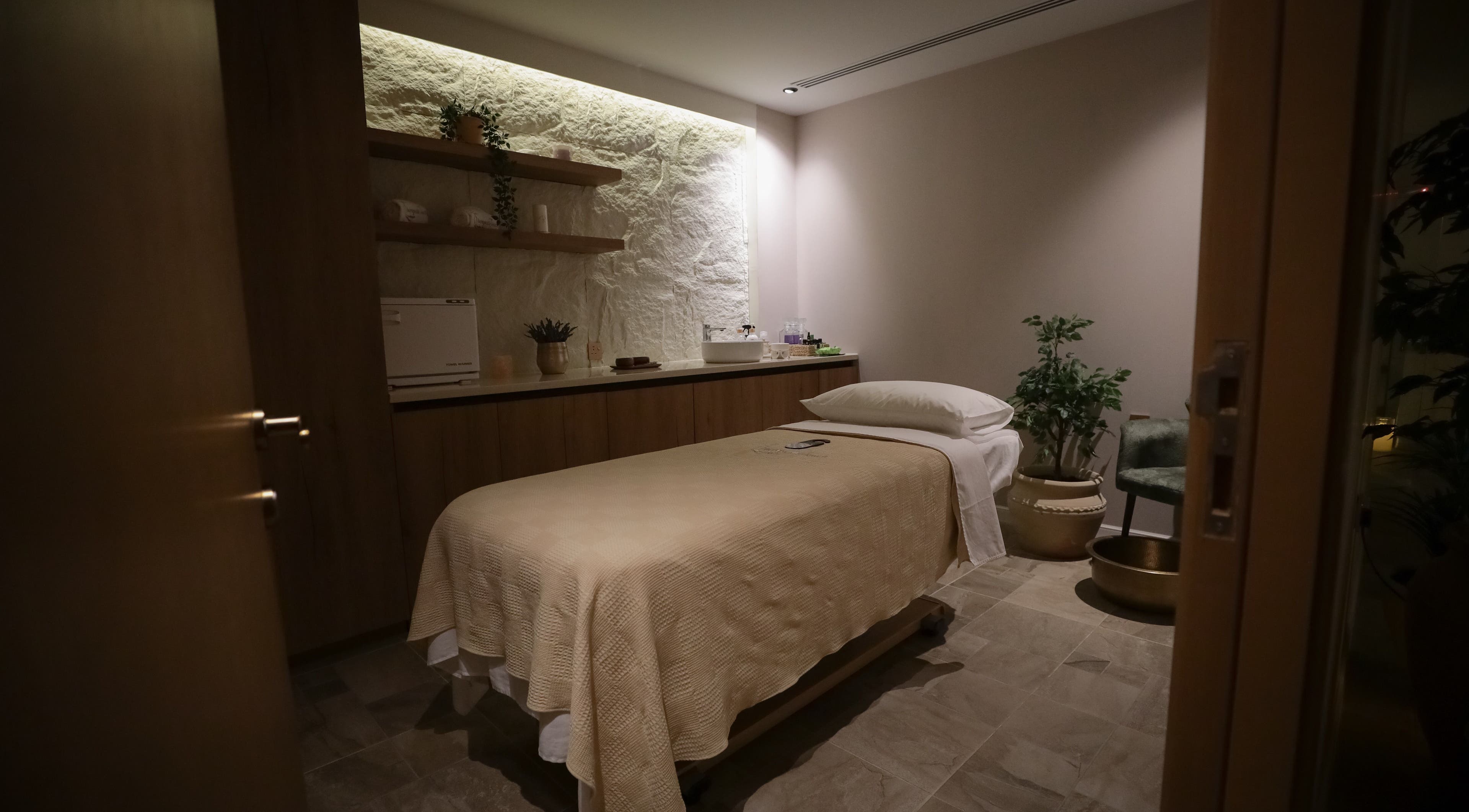 غرفة سبا مريحة في Therapeutic Touch، الخبر، المنطقة الشرقية، السعودية، مع سرير تدليك ونباتات هادئة.