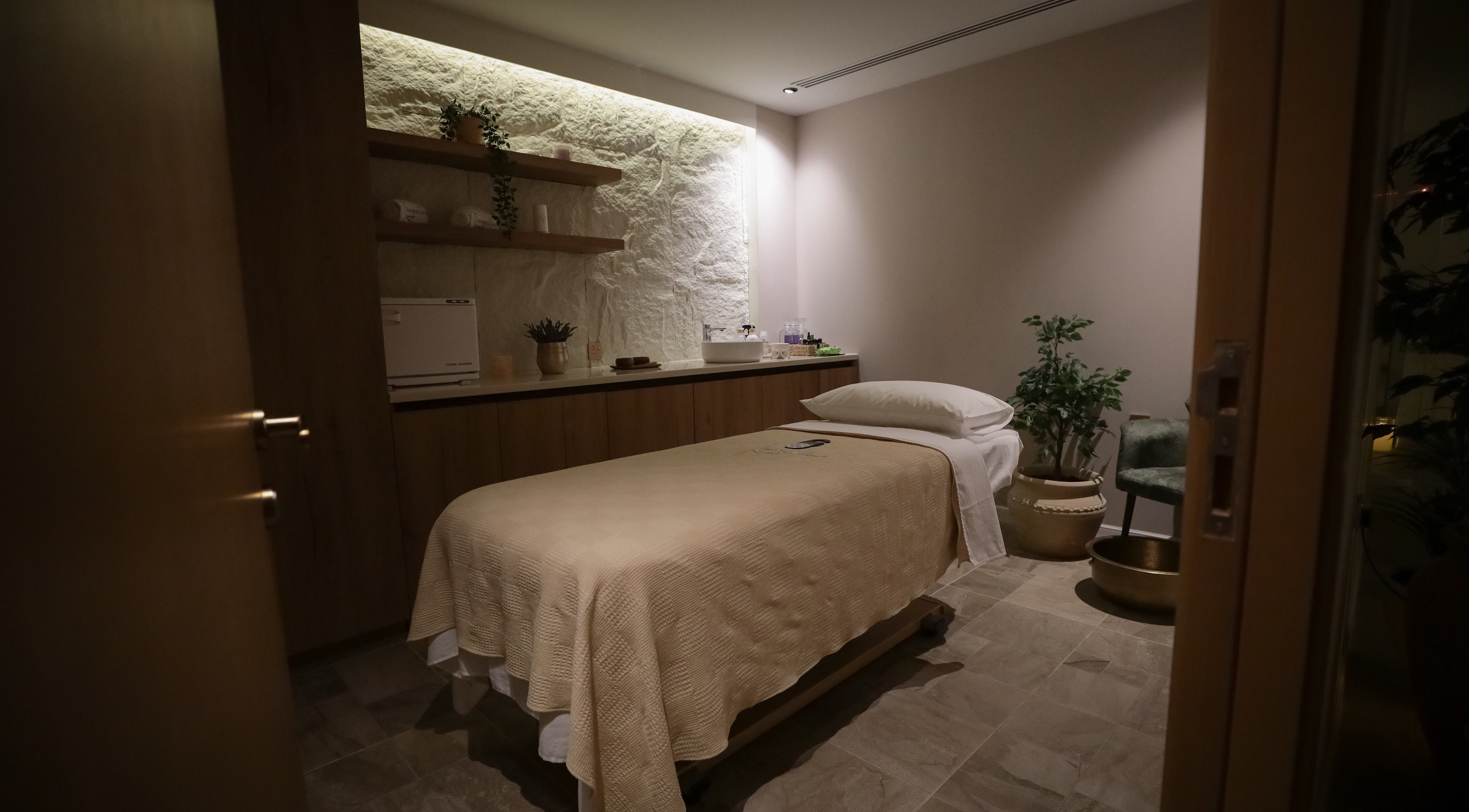 غرفة سبا مريحة في Therapeutic Touch، الخبر، المنطقة الشرقية، السعودية، مع سرير تدليك ونباتات هادئة.