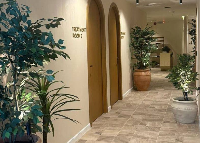 ممر هادئ في Therapeutic Touch بمدينة الخبر، المنطقة الشرقية، SA مع نباتات خضراء وغرف علاج مريحة.