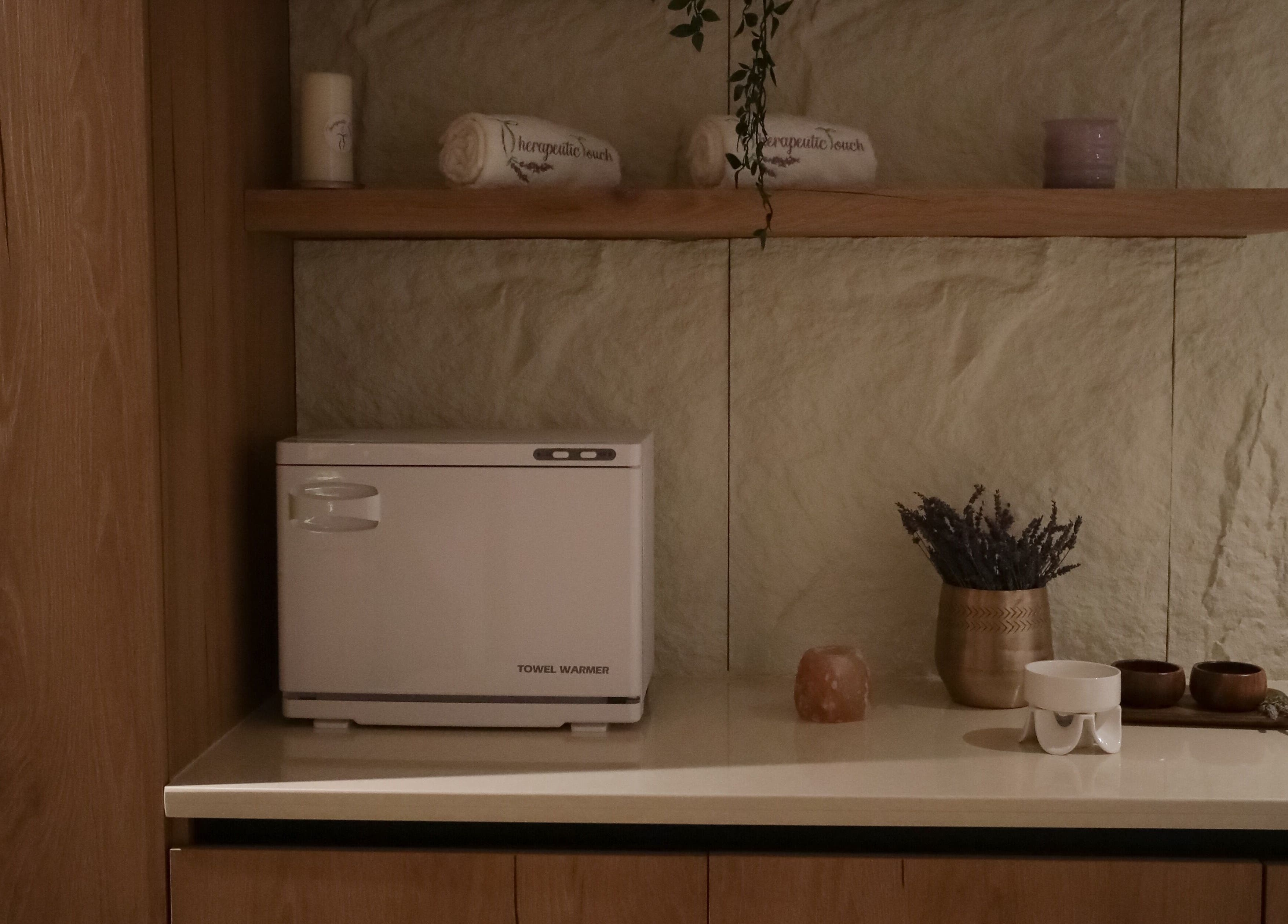 ركن مريح في Therapeutic Touch في الخبر، المنطقة الشرقية، يعرض رفاً بمنشفة، شمعة وعطر.