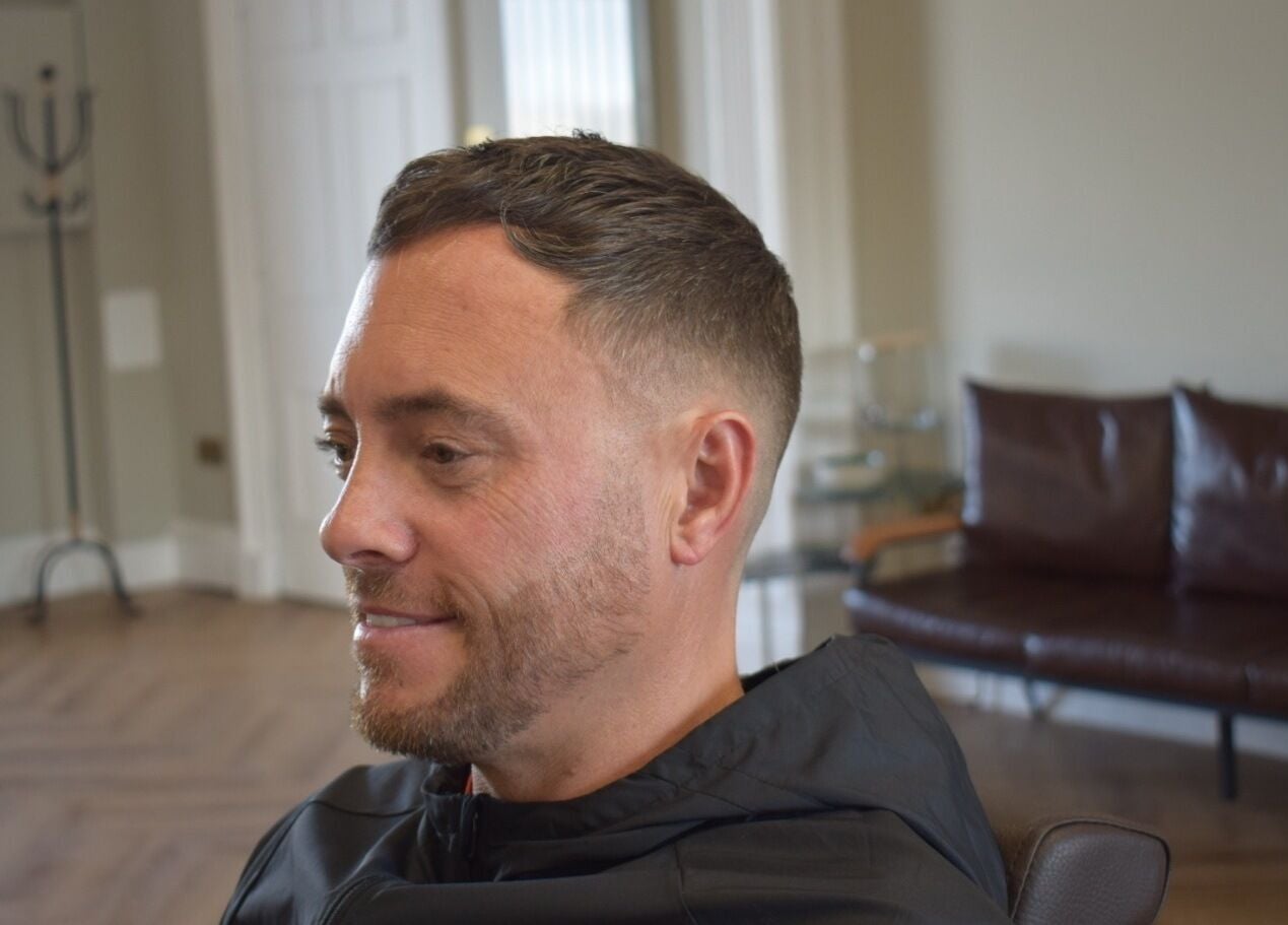 A man with a fresh fade haircut sits smiling at His Grooming, Ayr, Scotland, GB.
