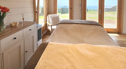 Peaceful treatment room at By Lana Grace, Ludgvan, England, GB with a cozy bed and scenic view.