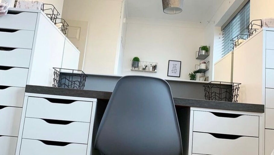 Modern beauty workspace at Kailey’s Beauty Room, Lowestoft, England, GB with sleek white drawers and black chair.