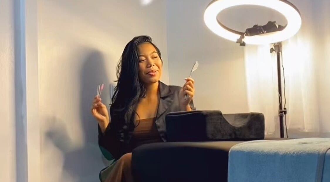 Vrouw in Doll Eye Studio, Paramaribo, ontspannen onder ringlicht tijdens een schoonheidsbehandeling.