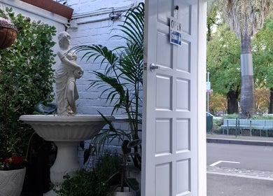 Entrance of Little Pigeon Massage and Waxing in Melbourne, with statue and greenery.