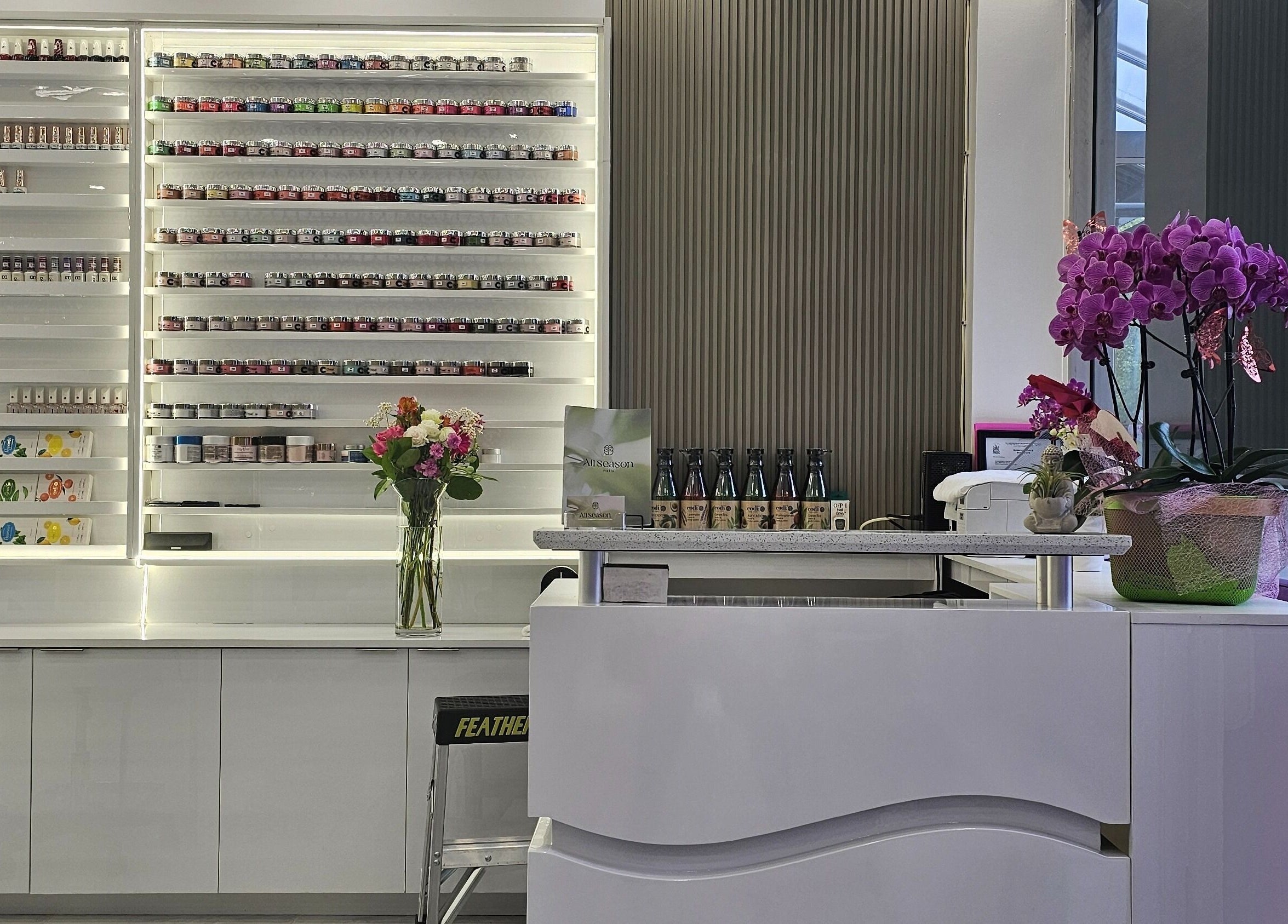 Elegant interior of All Season Nails (Westview), Vancouver, showcasing nail polish display and orchids.