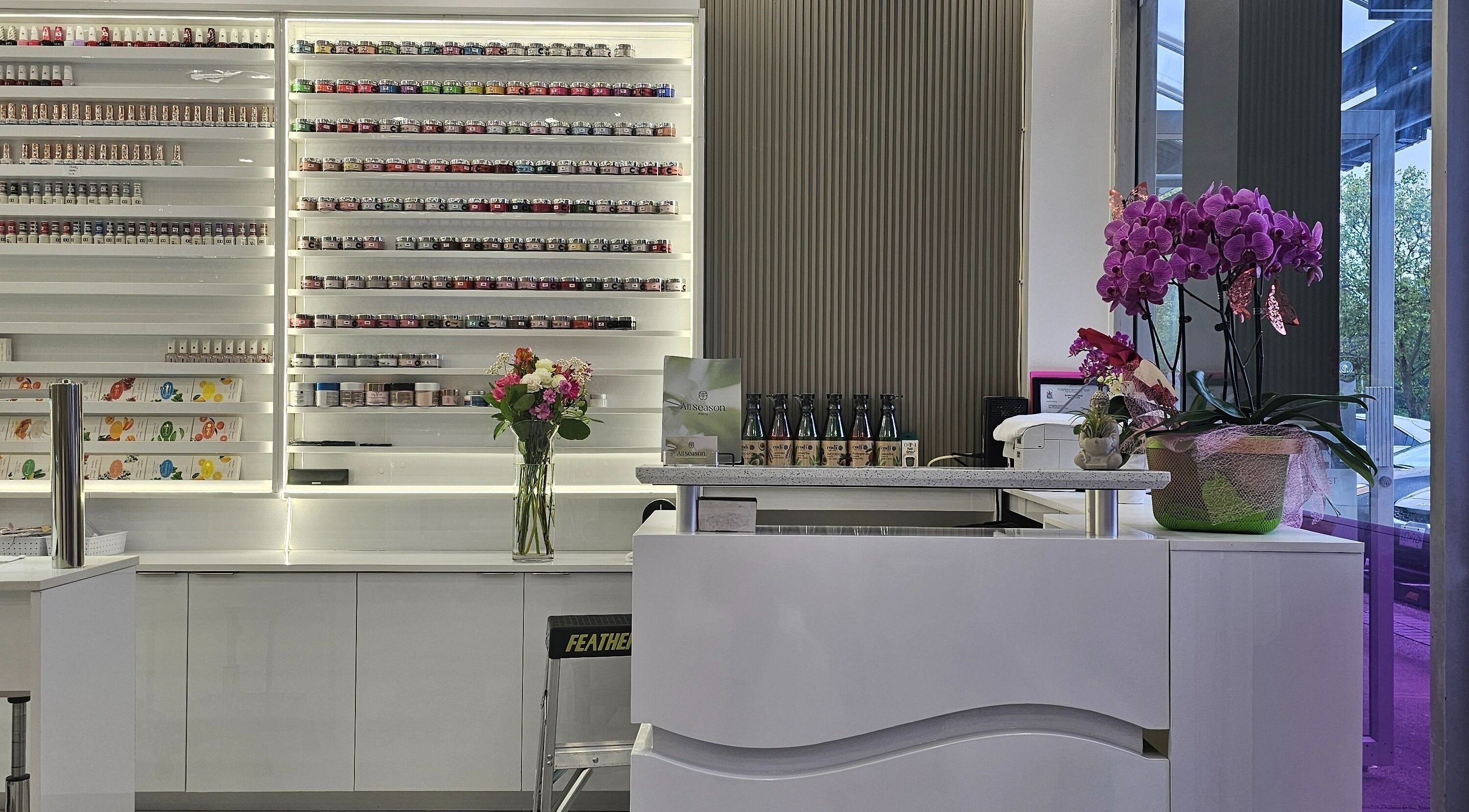 Elegant interior of All Season Nails (Westview), Vancouver, showcasing nail polish display and orchids.