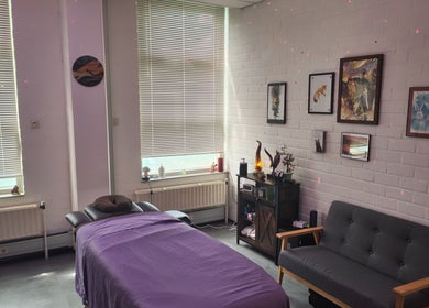 Calming massage room at Kneed Me: Massage Therapy, Amsterdam, Noord-Holland, NL with purple bed and cozy seating.