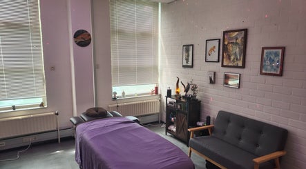 Calming massage room at Kneed Me: Massage Therapy, Amsterdam, Noord-Holland, NL with purple bed and cozy seating.