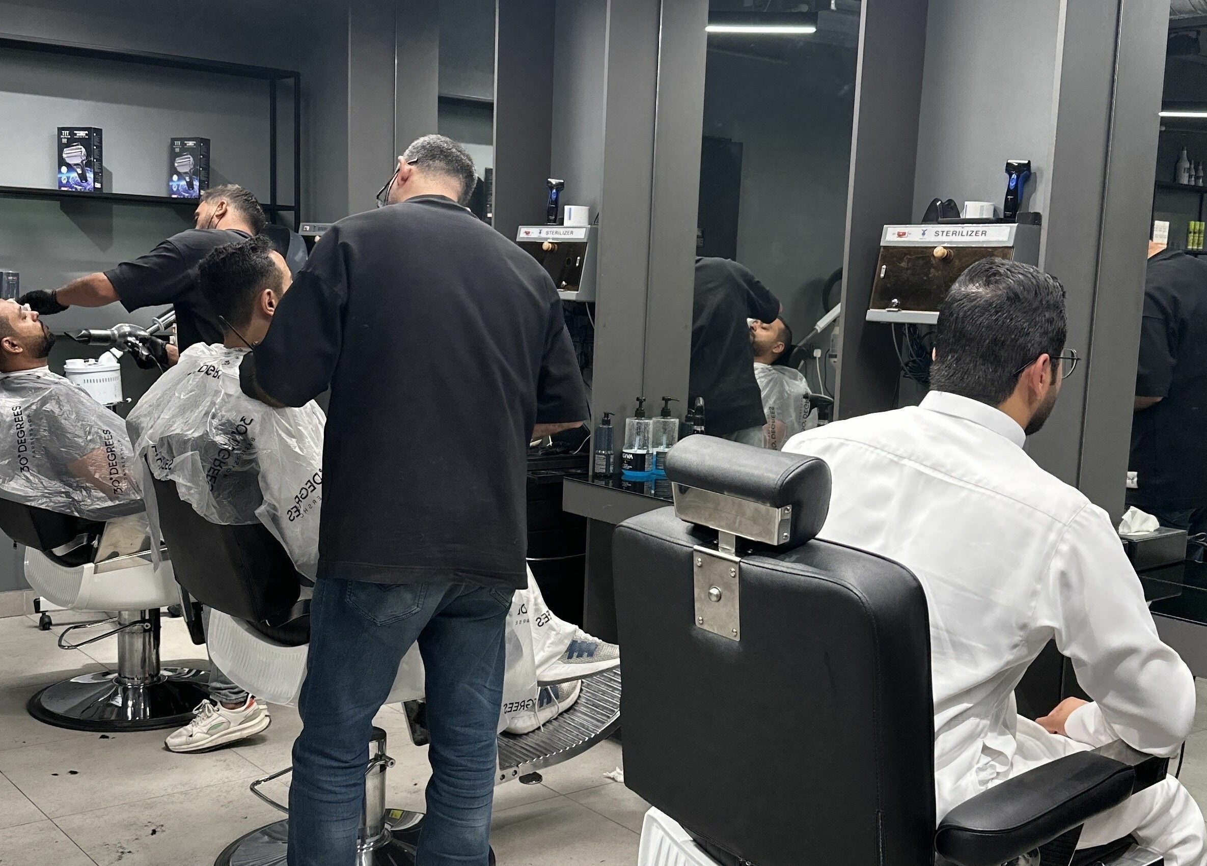 Interior of Al Izdihar 30 Degrees Barbershop, Riyadh, showing stylish haircuts in progress.