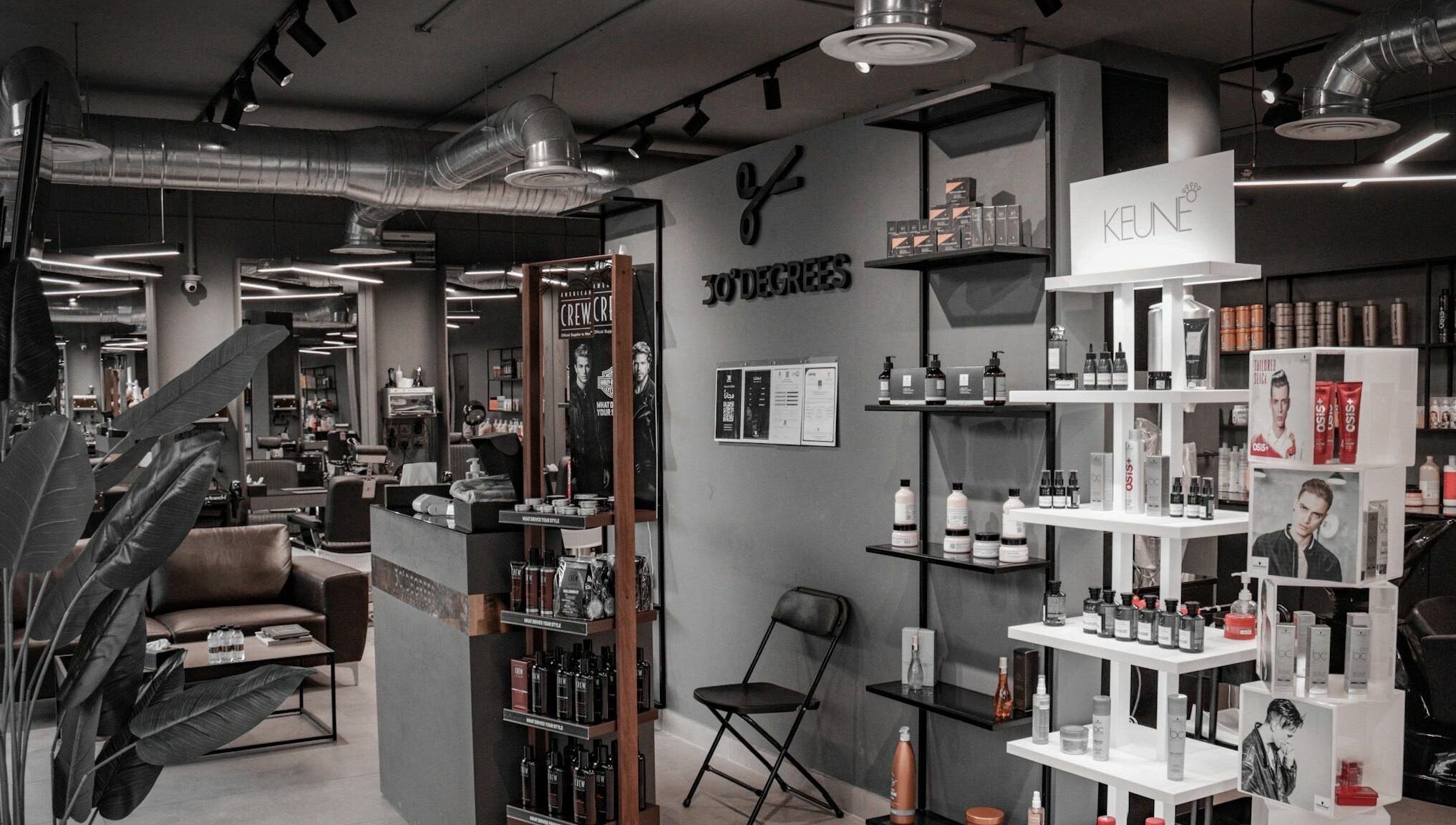 Interior view of Al Mohamadyah 30 Degrees Barbershop, Riyadh, showcasing sleek design and product displays.