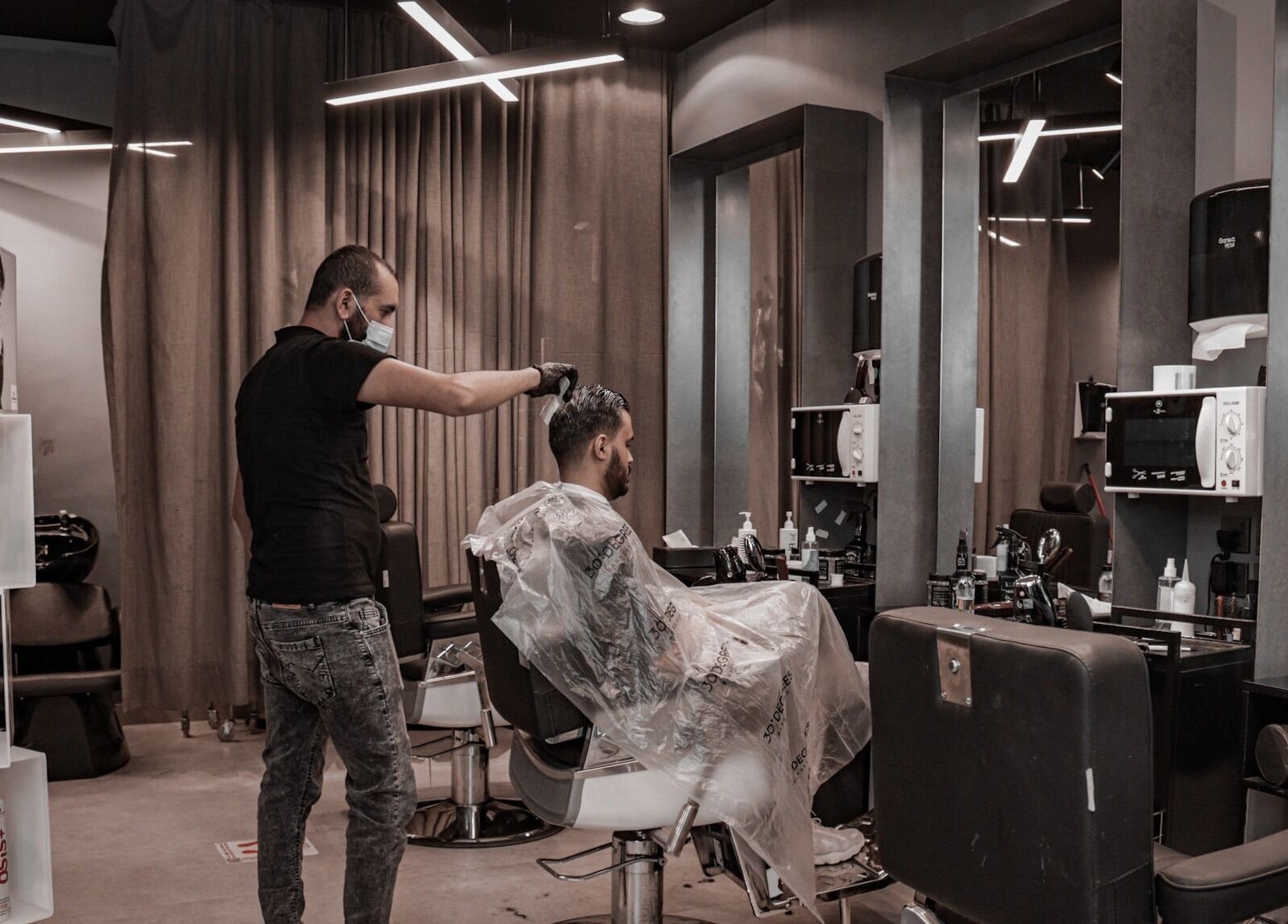A barber styles a client's hair at Qurtubah 30 Degrees Barbershop, Riyadh, Riyadh Province, SA.