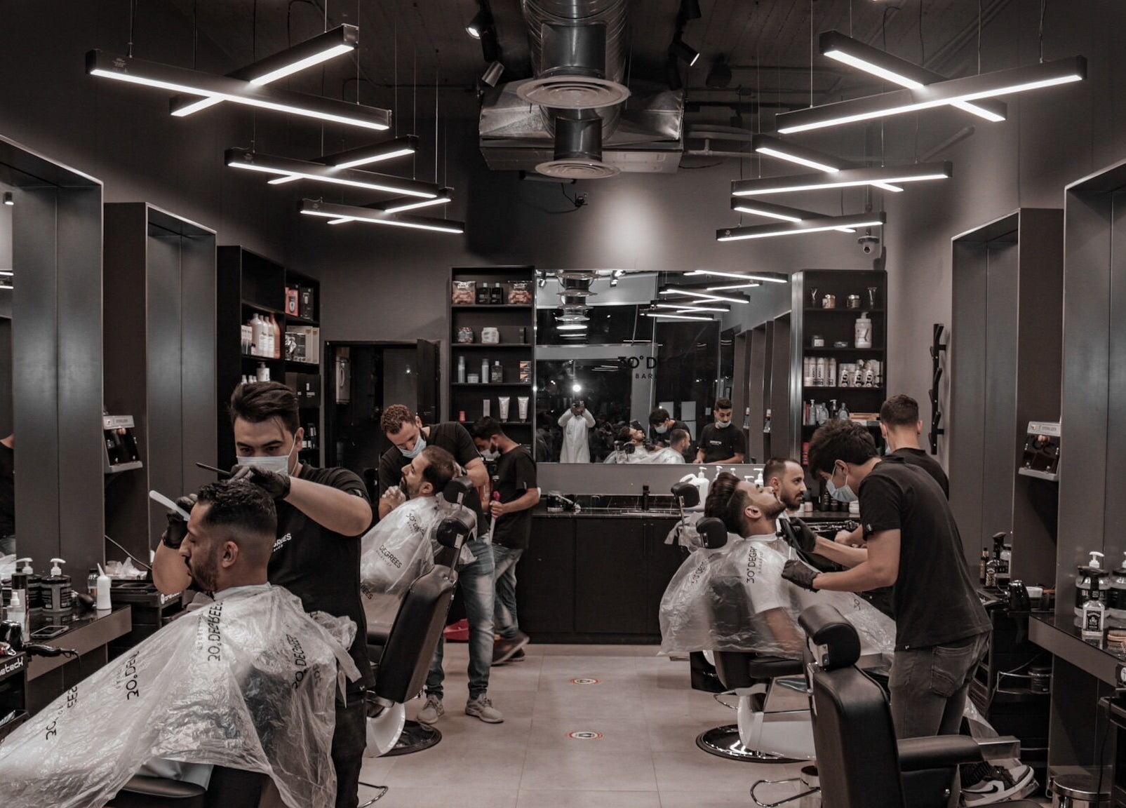 Stylish barber interior at Hittin 30 Degrees, Riyadh, Riyadh Province, SA with customers getting haircuts.