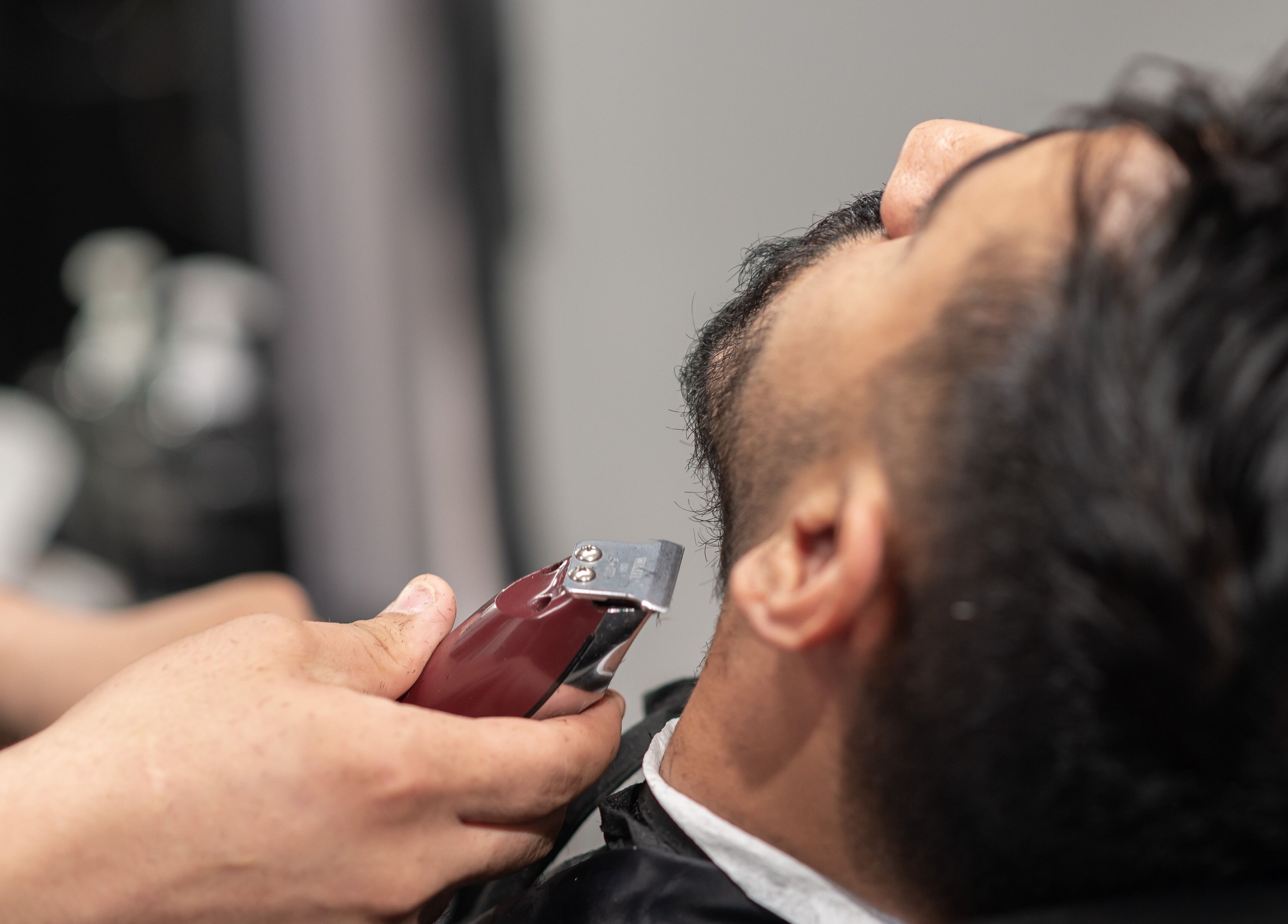 Barber trims beard at Al Malqa 30 Degrees, Riyadh, Riyadh Province, SA, offering expert grooming services.