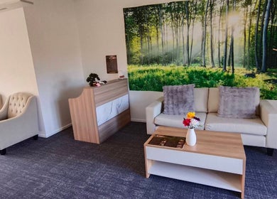 Relaxing reception at Darawan Thai Massage, Auckland, NZ with forest artwork and cozy seating.