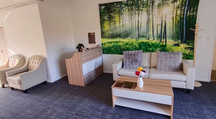 Relaxing reception at Darawan Thai Massage, Auckland, NZ with forest artwork and cozy seating.
