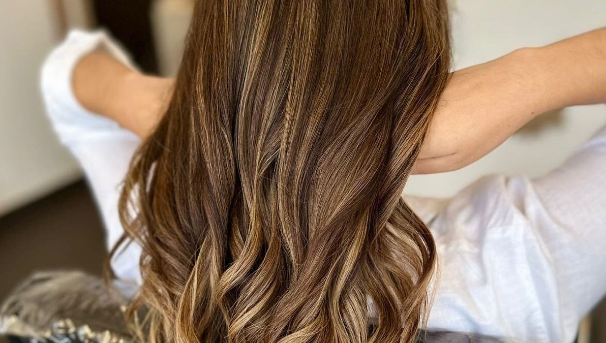 Cabello ondulado castaño en GLAM & GLOW Solidaridad, MX, destacando en un entorno elegante.