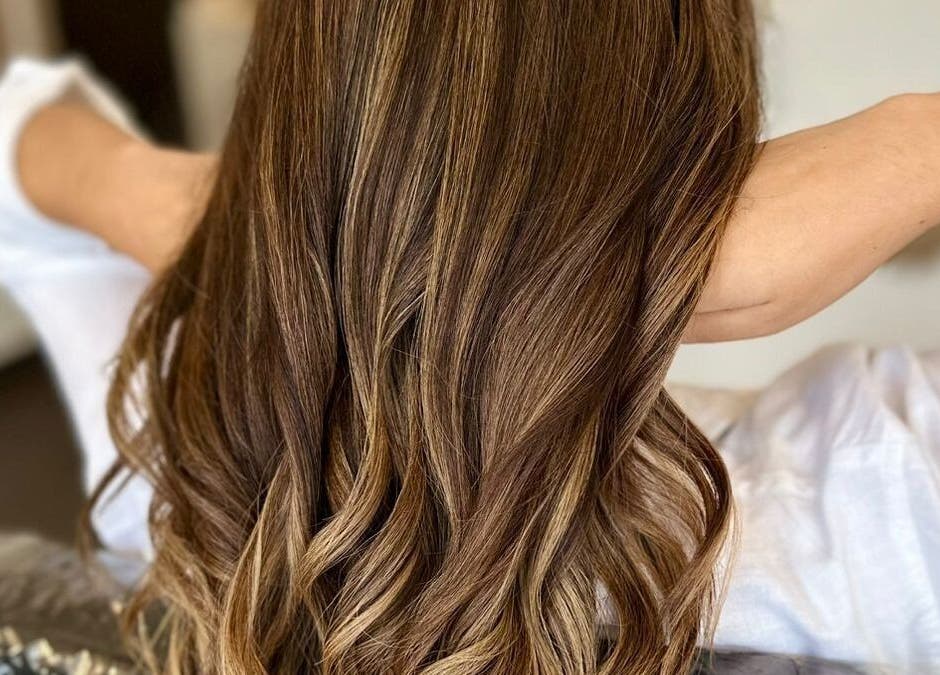 Cabello ondulado castaño en GLAM & GLOW Solidaridad, MX, destacando en un entorno elegante.