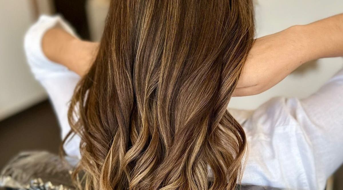 Cabello ondulado castaño en GLAM & GLOW Solidaridad, MX, destacando en un entorno elegante.