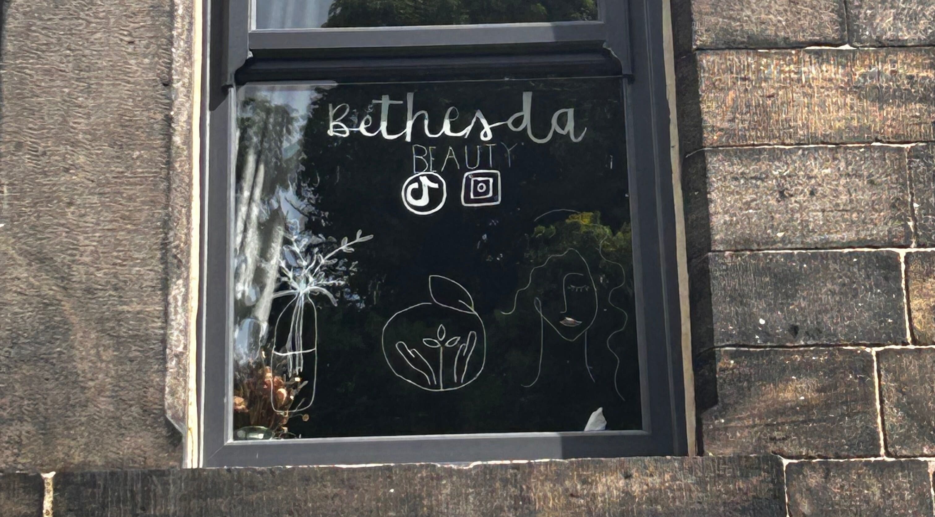 Window display at Bethesda Beauty, Rawdon, England, GB showcasing artistic designs and logo.