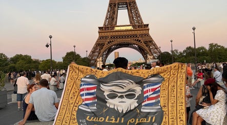 شخص يحمل لافتة صالون الهرم الخامس للحلاقة الرجالية أمام برج إيفل في الرياض, منطقة الرياض, SA.