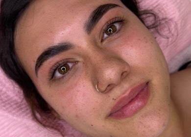 Patient at M&M BEAUTY after facial treatment in Kelso, Queensland, AU with glowing skin on a pink towel.