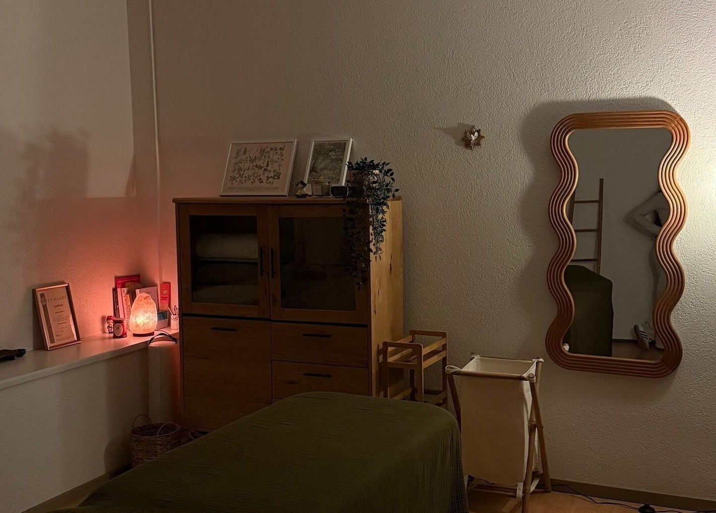 Espace apaisant chez Les mots du corps, Yverdon-les-Bains, Vaud, CH, avec miroir ondulé et éclairage doux.