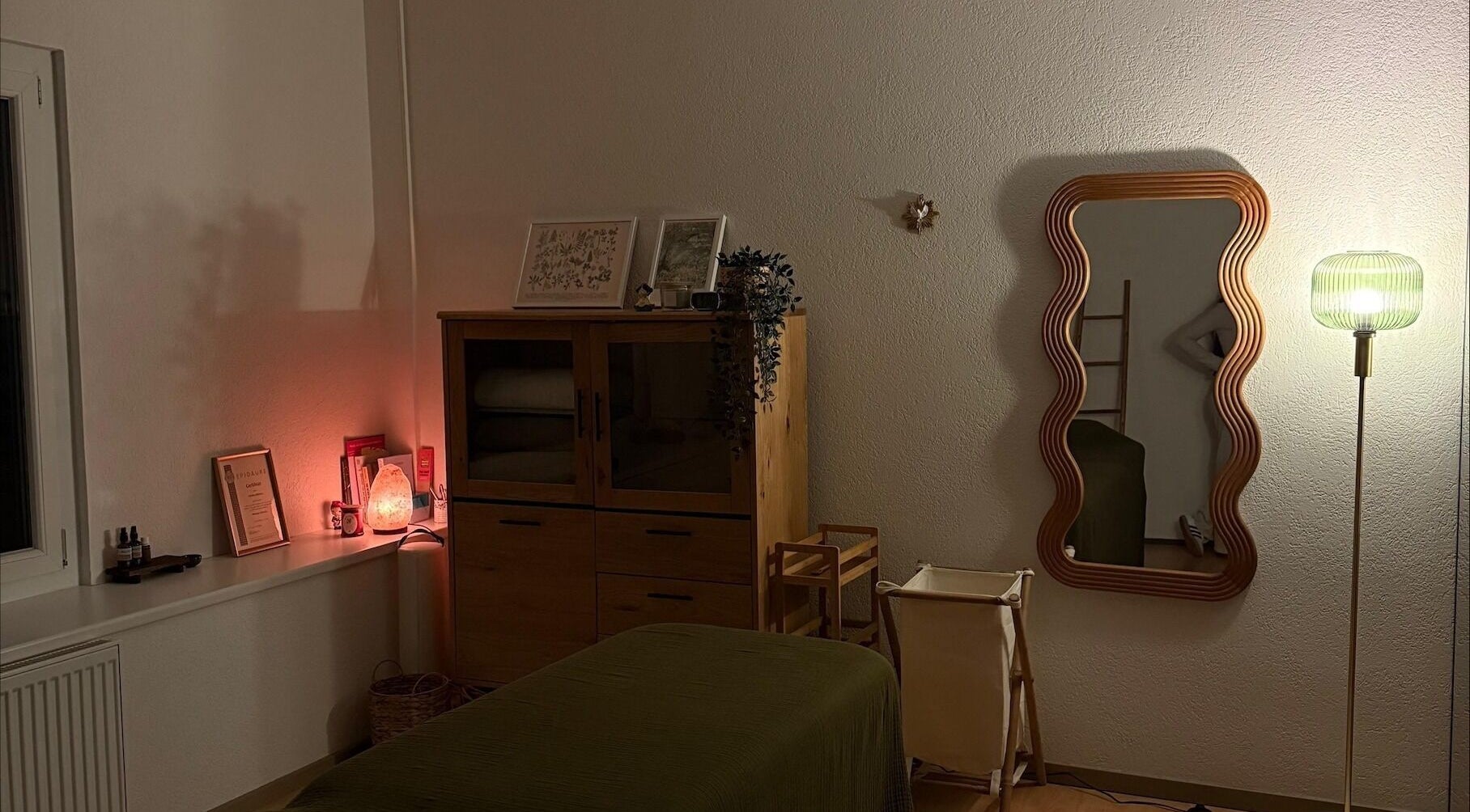 Espace apaisant chez Les mots du corps, Yverdon-les-Bains, Vaud, CH, avec miroir ondulé et éclairage doux.