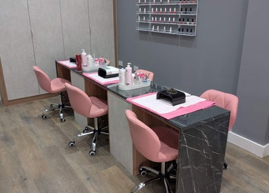 Modern nail stations at Glowfinity - Woodley, Woodley, England, GB, featuring pink chairs and a nail polish display.