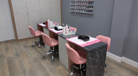 Modern nail stations at Glowfinity - Woodley, Woodley, England, GB, featuring pink chairs and a nail polish display.