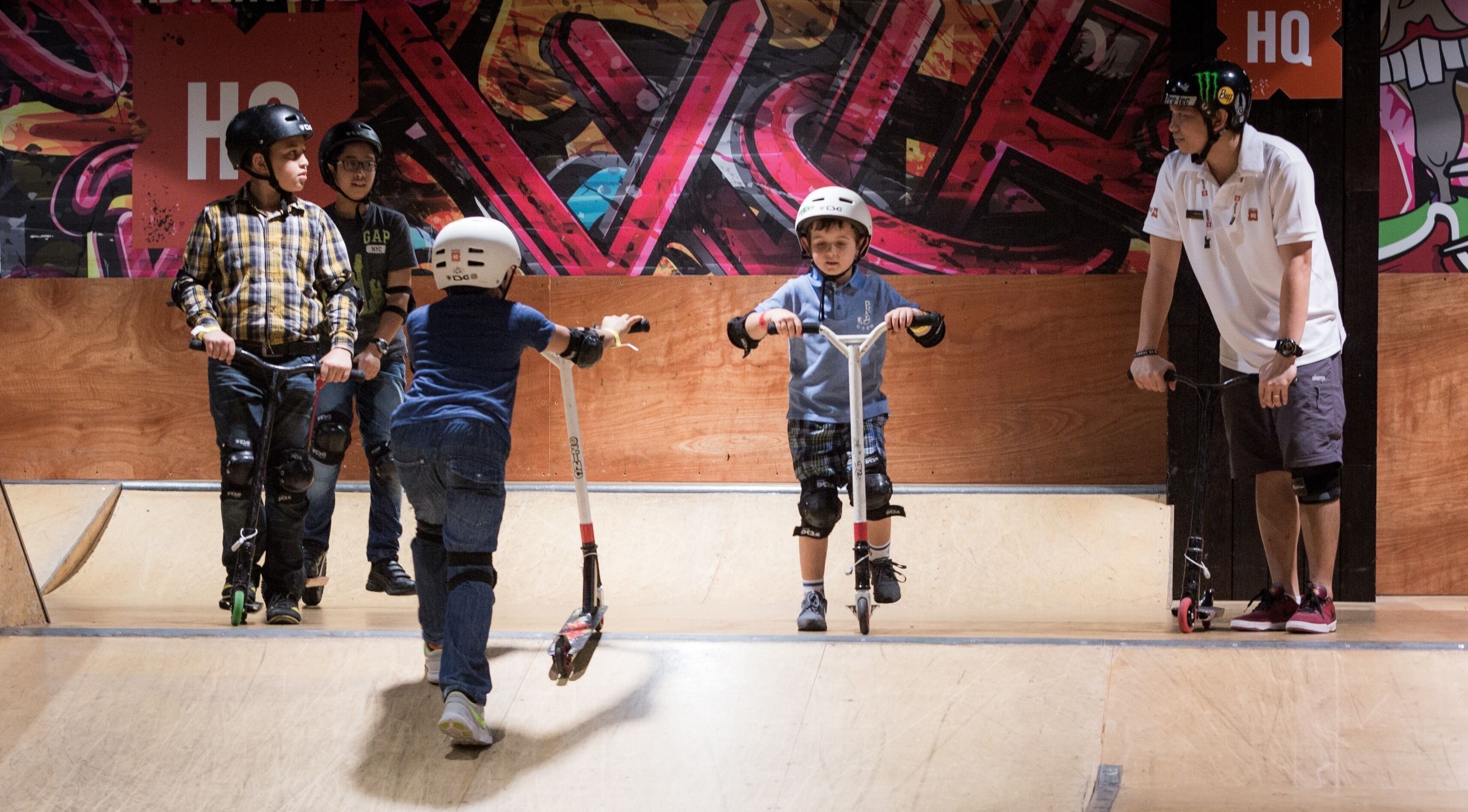 Children riding scooters at Adventure Zone, Dalma Mall, Abu Dhabi, AE. Indoor play area with colorful graffiti.