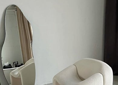 Elegant modern chair by wave mirror at GLAMBY GIA, Melbourne, Victoria, AU. Ideal for serene ambiance.
