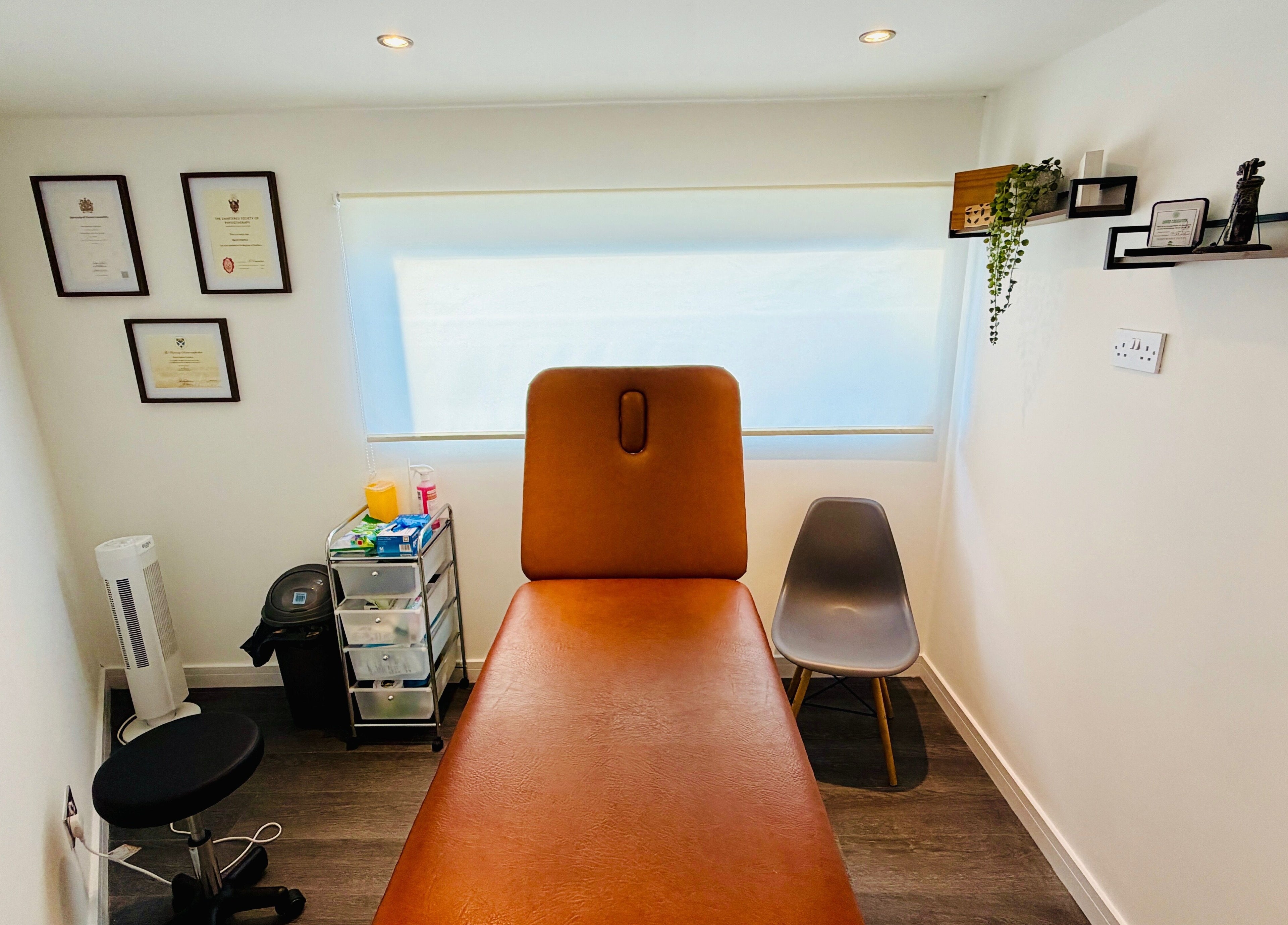 Cozy therapy room at Deaconsbank Physiotherapy, Glasgow, Scotland, GB with treatment bed and certificates.