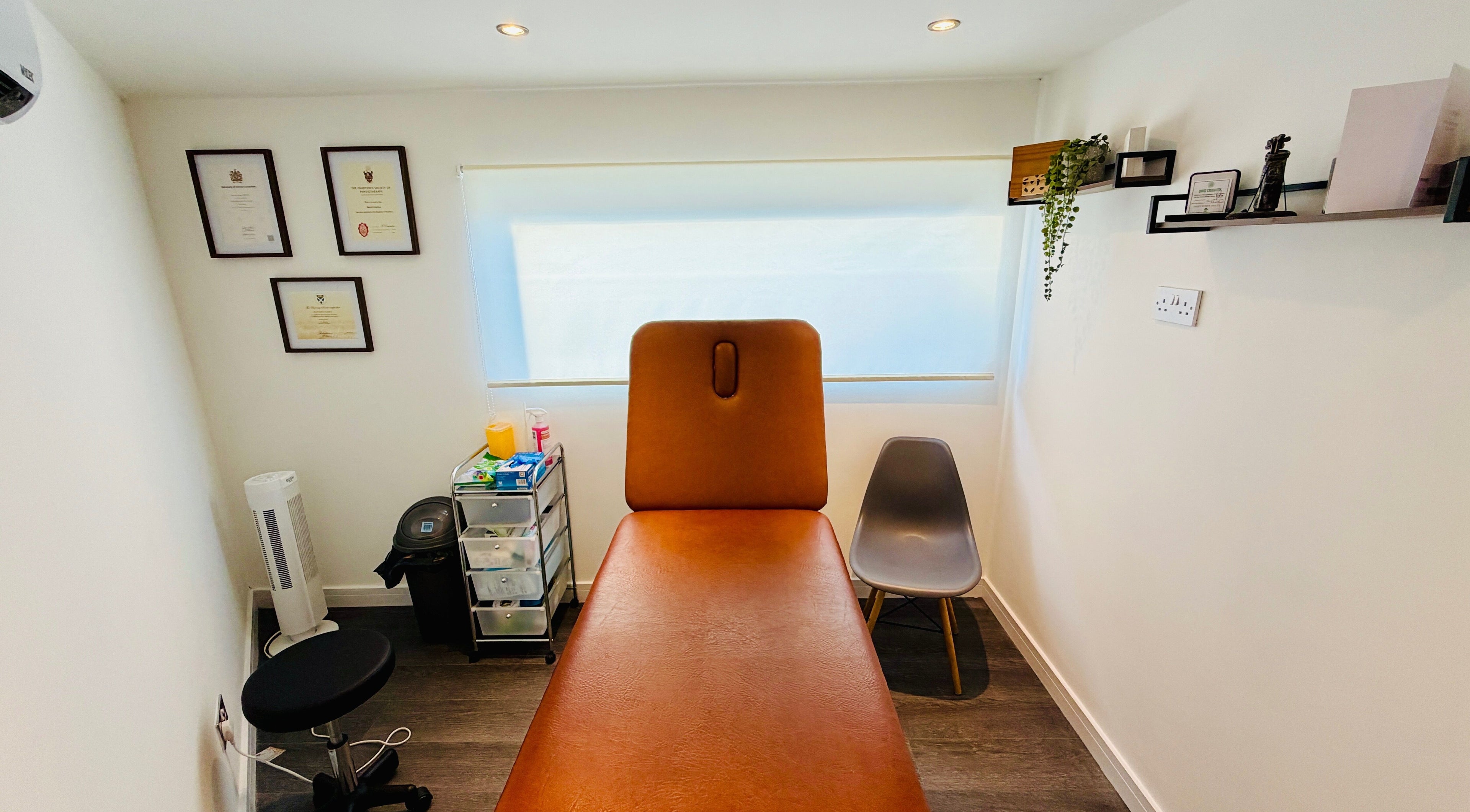 Cozy therapy room at Deaconsbank Physiotherapy, Glasgow, Scotland, GB with treatment bed and certificates.