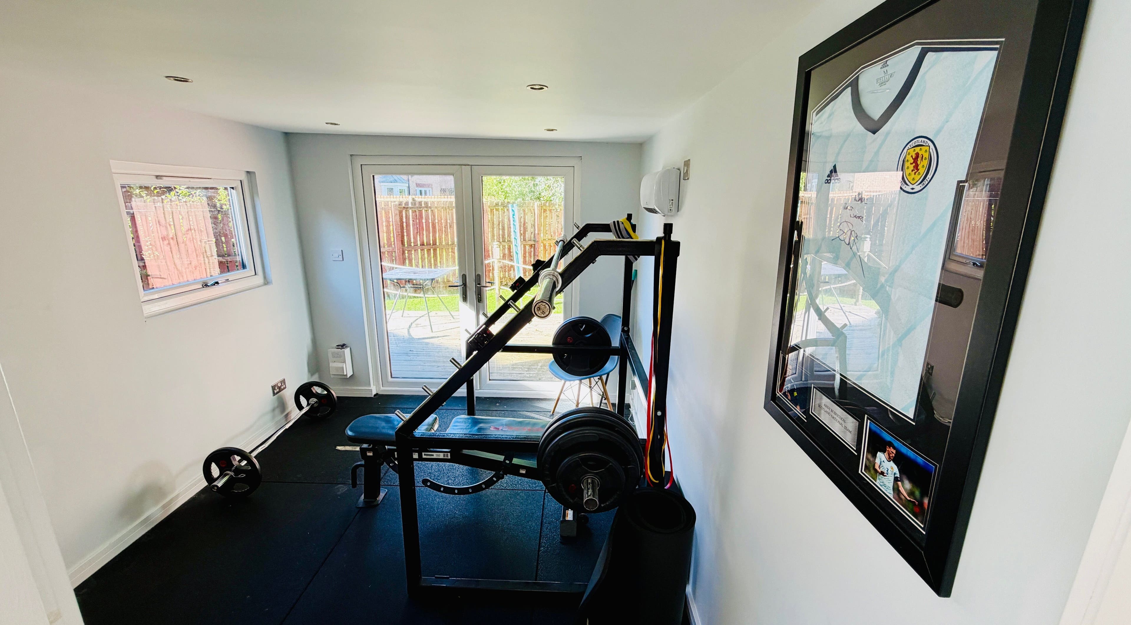 Modern gym at Deaconsbank Physiotherapy, Glasgow, Scotland, GB, featuring weightlifting equipment and bright decor.
