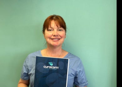 Smiling professional at Coventry Foot Clinic Whoberley, CV5 8BH, England, GB, holding a Curacorn booklet.