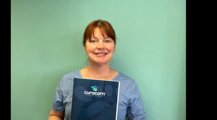 Smiling professional at Coventry Foot Clinic Whoberley, CV5 8BH, England, GB, holding a Curacorn booklet.