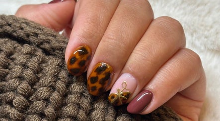 Stylish tortoiseshell nails by IC Nails in Aylesbury, England, GB, featuring elegant patterns and a bow accent.