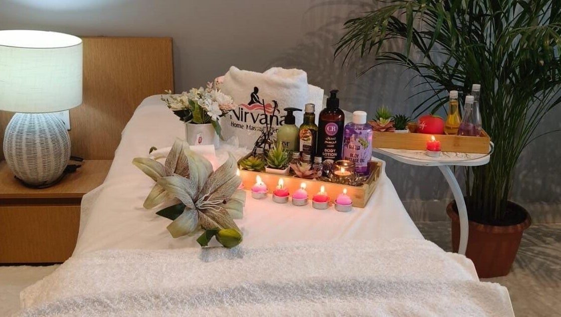 Tranquil spa setup at Nirvana Home Spa Service, Dubai, Dubai, AE with candles, oils, and fresh flowers.