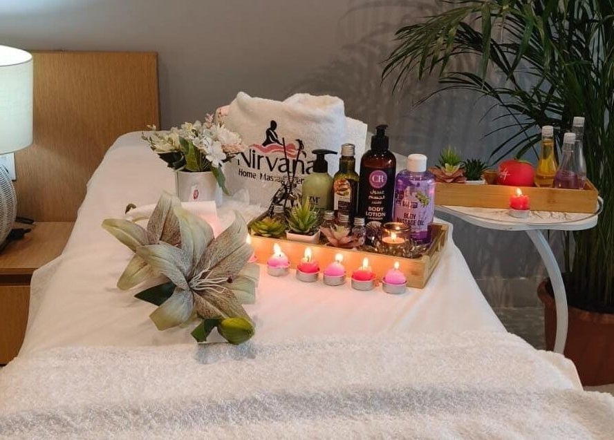 Tranquil spa setup at Nirvana Home Spa Service, Dubai, Dubai, AE with candles, oils, and fresh flowers.
