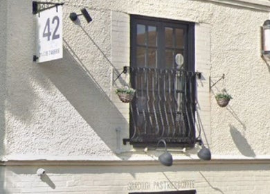 Front view of Beauty, Hair & Beyond's rustic exterior in Stevenage, England, GB, with hanging plants.