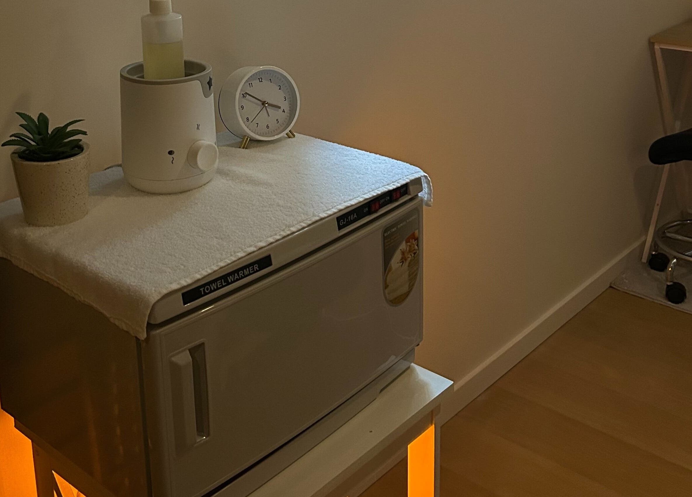 Cozy nook at Skin Deep Massage Therapy, Crib Point, Victoria, AU with towel warmer, plant, and clock.