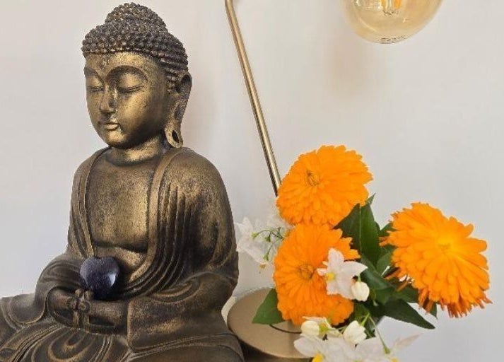 Buddha statue with orange flowers at Fern Wellbeing, Paignton, England, GB, enhancing tranquility and wellness.