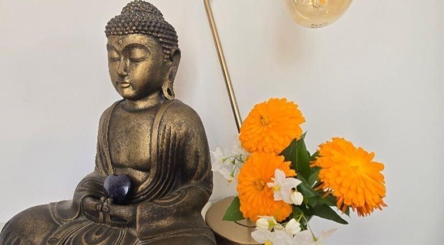 Buddha statue with orange flowers at Fern Wellbeing, Paignton, England, GB, enhancing tranquility and wellness.