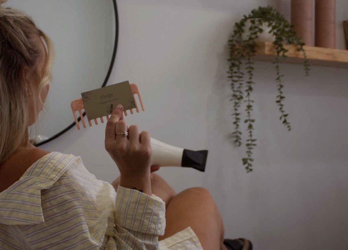 Woman holds A Designs comb at Killarney Vale, New South Wales, AU beauty salon.