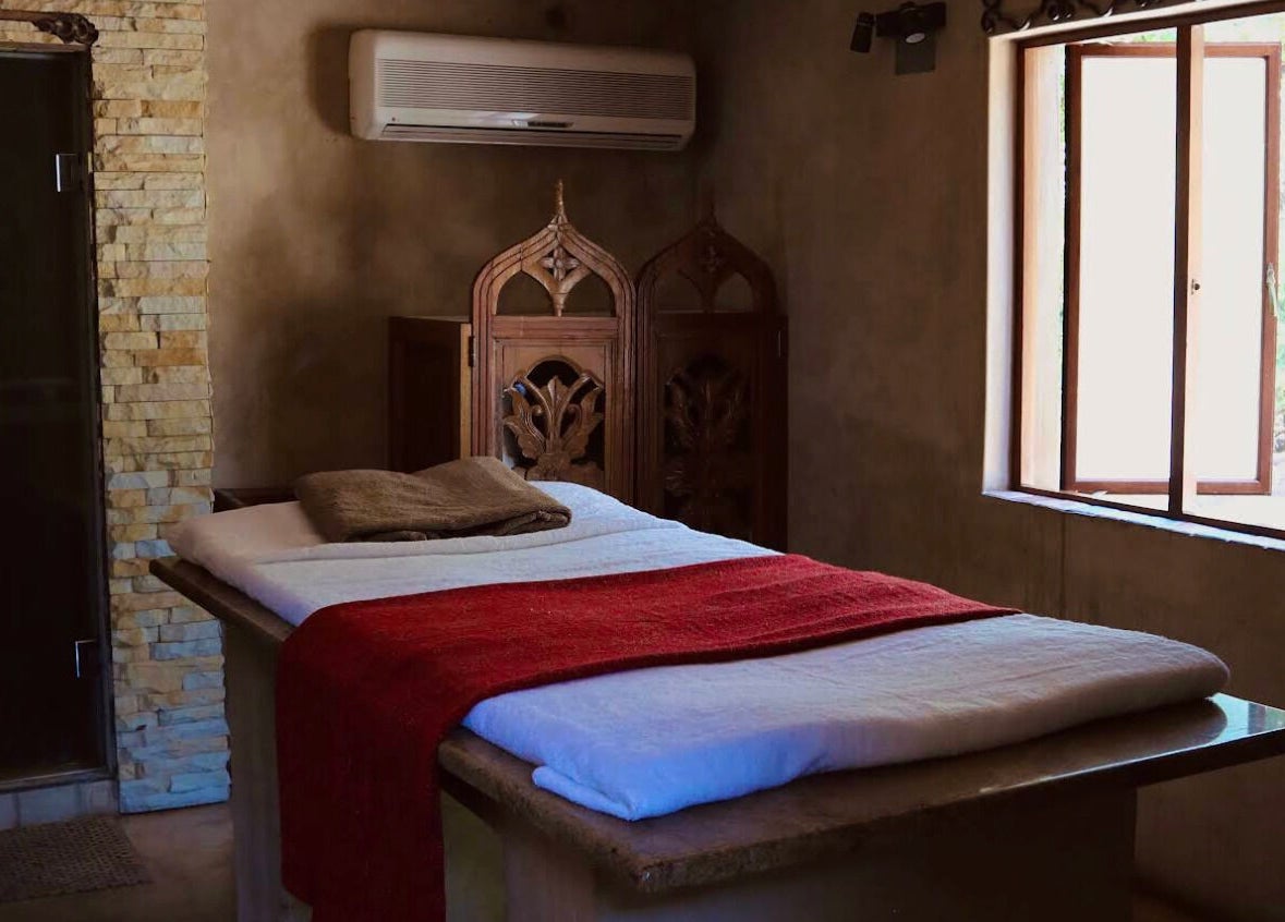 Cozy massage room at Bohemian Wellness & Spa, Pretoria, Gauteng, ZA with stone walls and a red blanket.